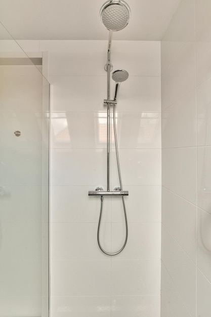 Photo a bathroom with a shower head and hand held in front of the shower stall which is white tile on the floor