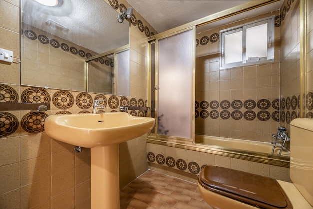 Bathroom with vintage tiles frameless mirror and cream porcelain toilets