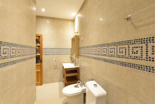 Bathroom with white porcelain sink with open wooden cabinet with mirror with matching frame and mosaic tiles with blue border