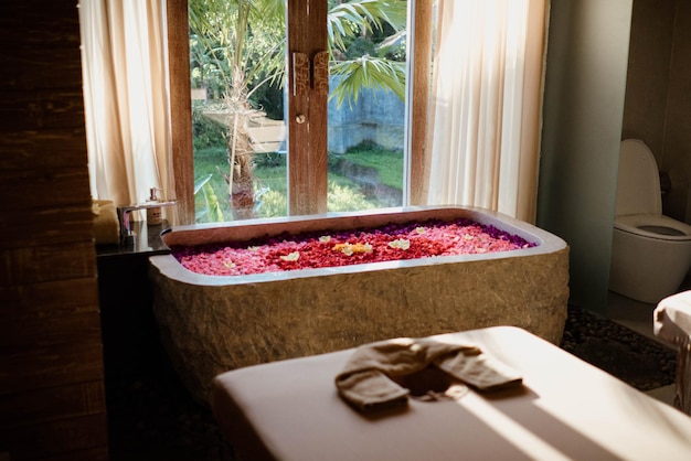 A bathtub with a flower bed in front of a window.