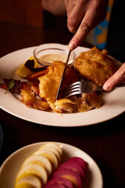 Battered fish on a plate with chips on a wooden table in pub unhealthy food