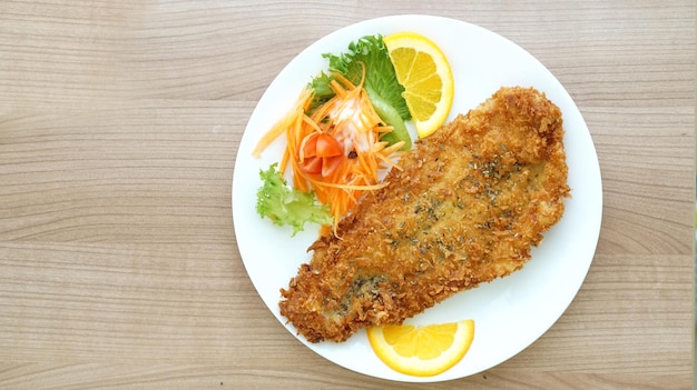 Photo battered fried fish steak with orange and salad