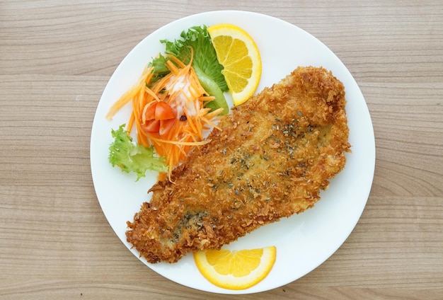 Photo battered fried fish steak with orange and salad