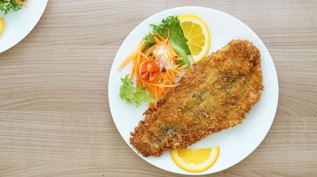 Photo battered fried fish steak with orange and salad