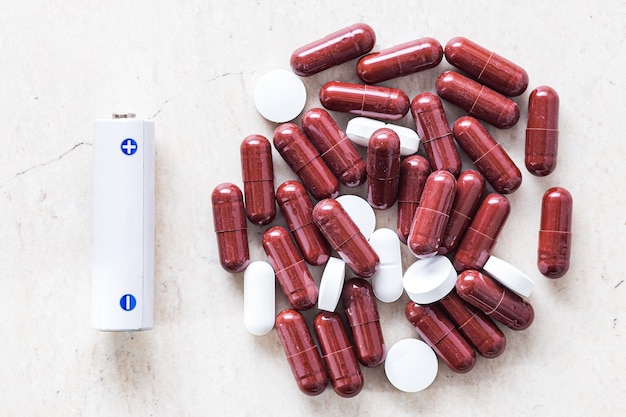 Batterij en witte pil geneeskunde, energie voor het leven, ideeBatterij en capsules en tabletten. energieconcept voor het leven