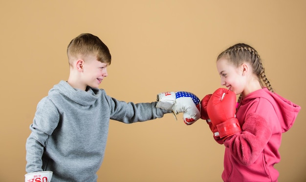 Battle for attention Child sporty athlete practicing boxing skills Boxing sport Children wear boxing gloves while fighting beige background Attack and defend Girl and boy boxing competitors