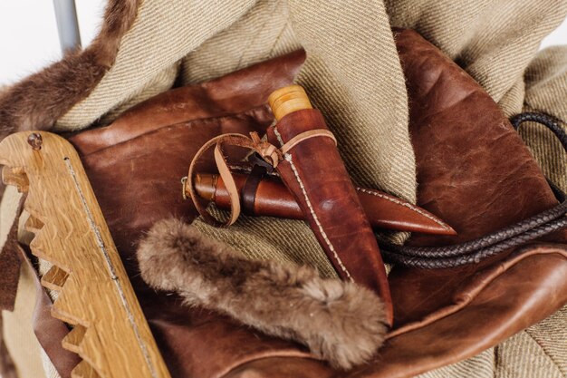 Battle hunting knife lying on the fur and clothes background View closeup