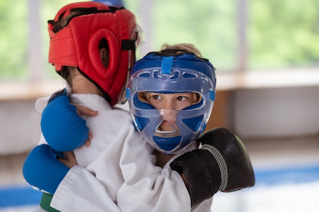 Battling with friend. Dark-eyed boy wearing protective helmet and gloves battling with friend