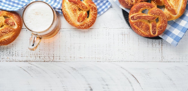 Bavarian pretzels and glass of lager beer Oktoberfest food menu traditional salted pretzels over old white wooden background Top view with space for text Oktoberfest theme