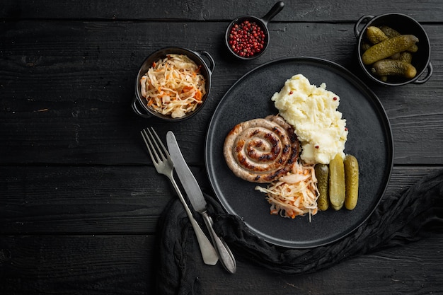 Bavarian sausage mashed potatoes and sour cabbage, on black wooden table background, top view flat lay , with space for text  copyspace