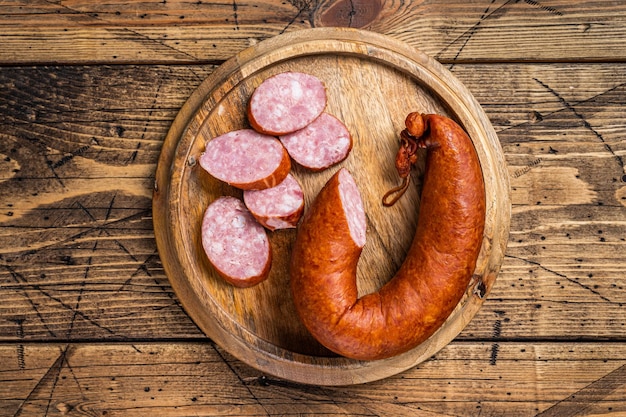 Bavarian Smoked sausage on a wooden board with herbs. White wooden background. Top view.