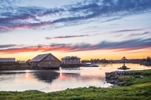 Bay of Prosperity op de Solovetsky-eilanden, een houten kruis en een biologisch stationsgebouw onder een prachtige zonsonderganghemel