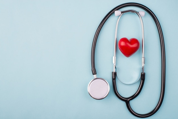 Bblack stethoscope and small red heart on blue background