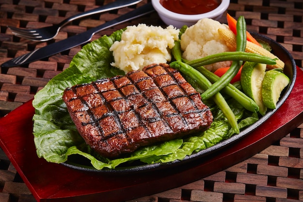 샐러드와 소스를 곁들인 BBQ 쇠고기 스테이크는 중동 음식의 탁자 측면에 격리된 접시에 제공됩니다.