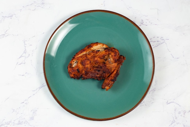 Bbq chicken breast piece served in a dish isolated on background side view