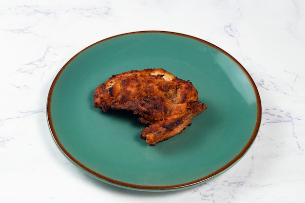 Bbq chicken breast piece served in a dish isolated on background side view