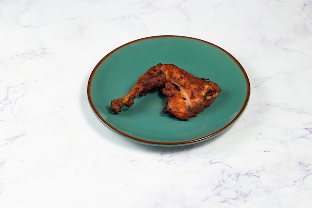 Bbq chicken leg piece served in a dish isolated on background side view