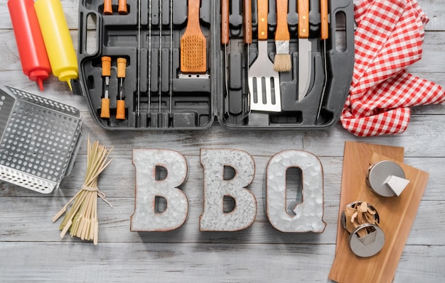 Photo bbq cooking set in the case on the wood background.