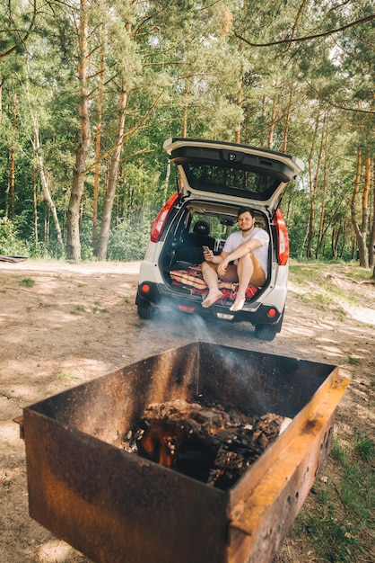 Bbq on fire man sitting in car trunk car travel concept