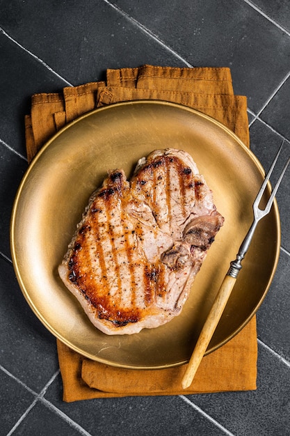 BBQ fried pork T bone chop meat steak on a plate Black background Top view