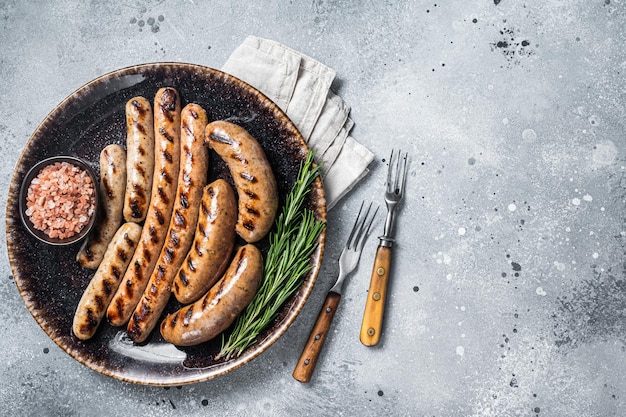 BBQ gebraden Bratwurst vlees worstjes op een bord met rozemarijn Grijze achtergrond Bovenaanzicht Kopieer ruimte