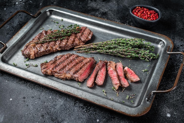 BBQ gebraden denver top blade beef steak op een stalen dienblad met kruiden zwarte achtergrond bovenaanzicht
