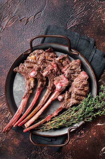 BBQ Gegrilde lamskotelet steak schapenvlees rib kotelet in stalen dienblad met tijm Donkere achtergrond Bovenaanzicht