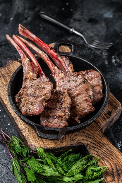Bbq gegrilde lamsvlees karbonades steaks in een pan zwarte achtergrond bovenaanzicht