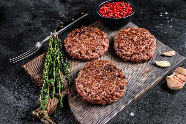 BBQ-gegrilde rundvlees pasteitjes voor hamburger van gehakt vlees en kruiden op een houten bord