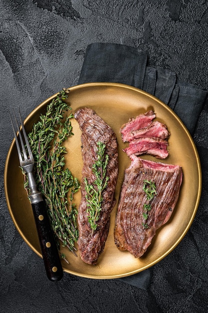 BBQ grilled Bavette Bavet beef meat steak with herbs on a plate Black background Top view