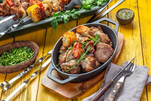 Мясо на гриле барбекю, свинина, курица и овощи на чугунной сковороде Жареные шашлычки на желтом деревянном фоне Вид сверху