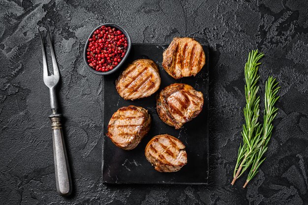 BBQ grilled pork medallions steaks tenderloin fillet meat Black background Top view