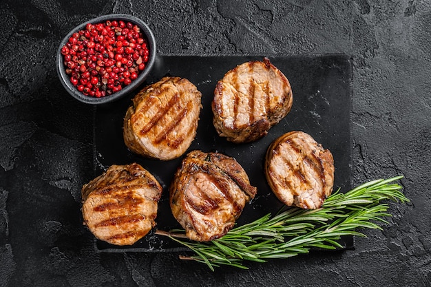 Foto barbecue medaglioni di maiale alla griglia bistecche filetto di lombo carne sfondo nero vista dall'alto