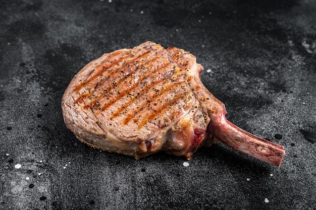 BBQ Grilled Tomahawk beef veal steak on butcher table Black background Top view