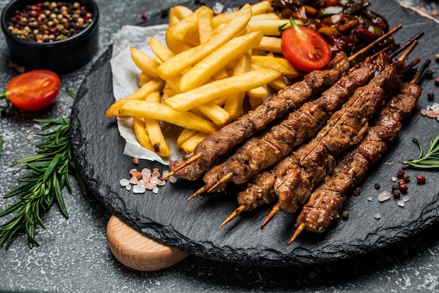 Bbq meat on wooden skewers with fries and vegetables georgian\
cuisine hearty lunch or dinner banner menu recipe place for text\
top view