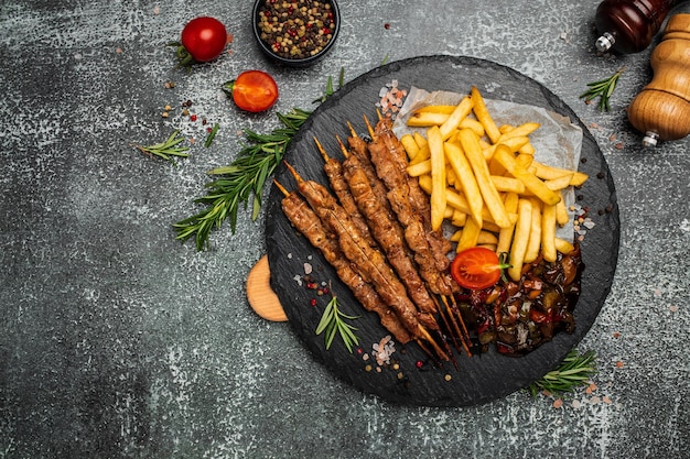 Bbq meat on wooden skewers with fries and vegetables Georgian cuisine hearty lunch or dinner banner menu recipe place for text top view