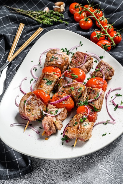bbq pork and beef meat on wooden skewers. gray background. top view.