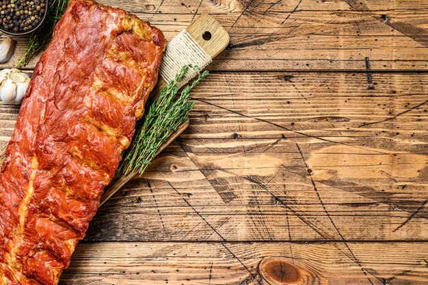 BBq pork ribs on a chopping board with herbs