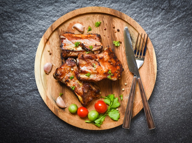 Bbq pork ribs grilled with tomatoes herbs and spices on wooden tray 