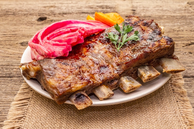 BBQ pork ribs with fermented cabbage, baked carrot and fresh parsley