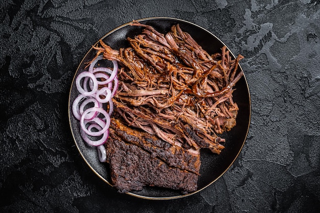 BBQ pulled pork meat on plate Black background Top view