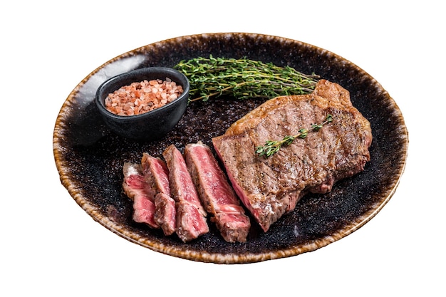 BBQ roast sliced New York beef steak on a plate with thyme and salt Isolated white background