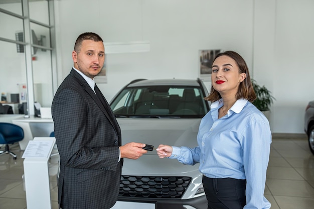 Photo bbusiness client shaking hands with sales agent in suit after buying a car in showroom
