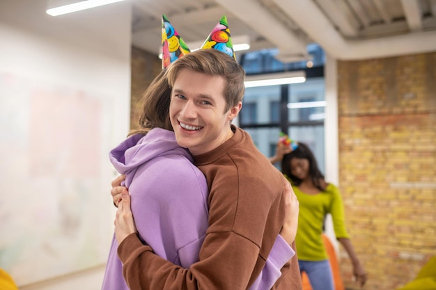 Bday party. a young guy hugging his colleagues and\
congartulating her with her bday