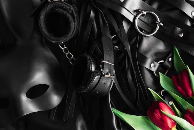 BDSM lederen set accessoires in de buurt van masker en bloemen