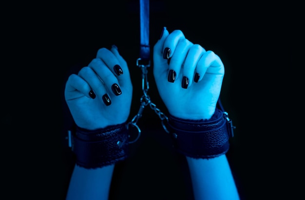 Girl in handcuffs and mask. in color lights. tied hands and