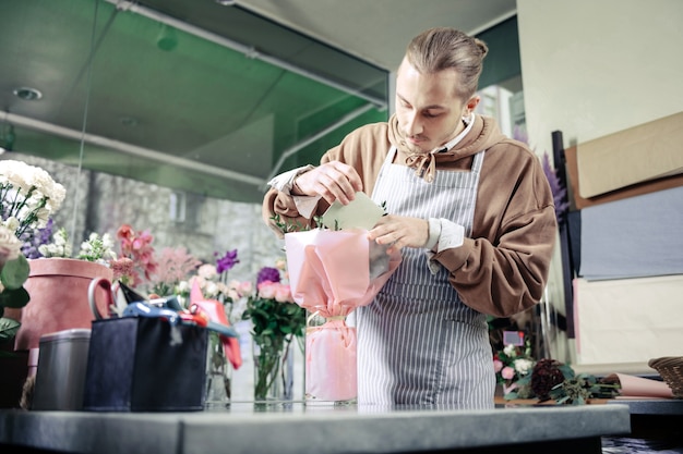 Be accurate. Attentive designer standing at his workplace and making bouquet