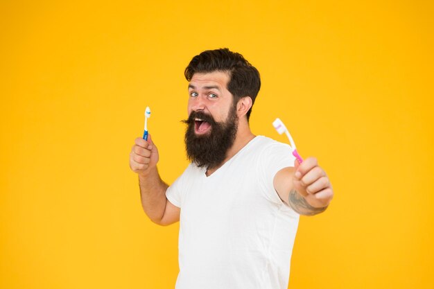 Be always healthy Bearded man hold toothbrushes Dentistry and oral health Healthy habits Dental care Tooth brushing Healthy mouth Keep teeth and gums healthy