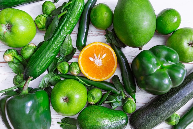 Photo be different concept orange surrounded by green fruits and vege