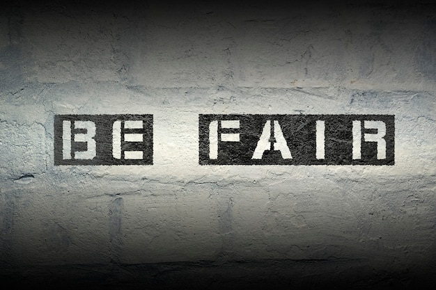 Be fair stencil print on the grunge white brick wall